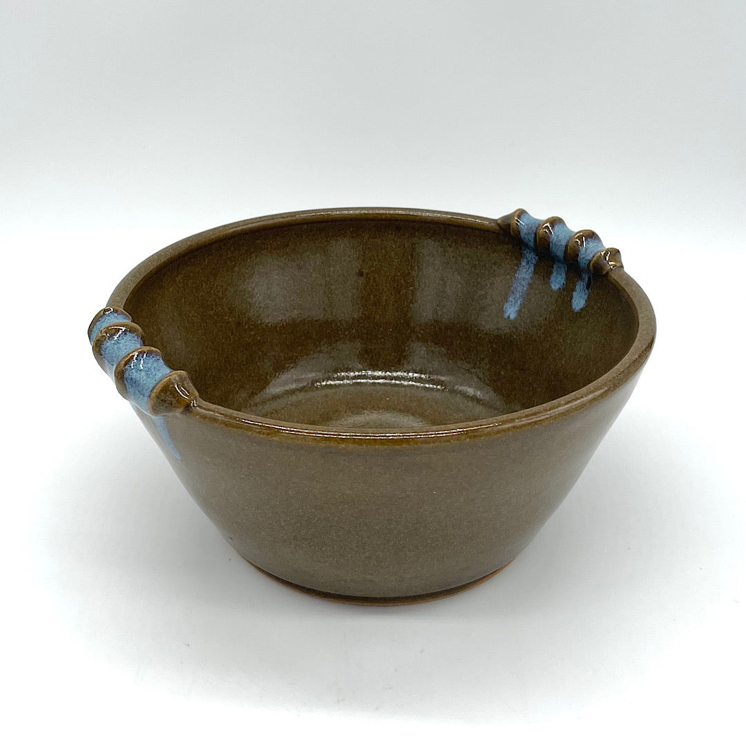 Handmade brown ceramic casserole with blue handles